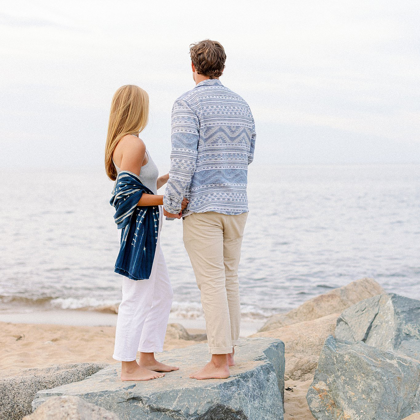 Couple hand in hand look out over the water at Plum Island.