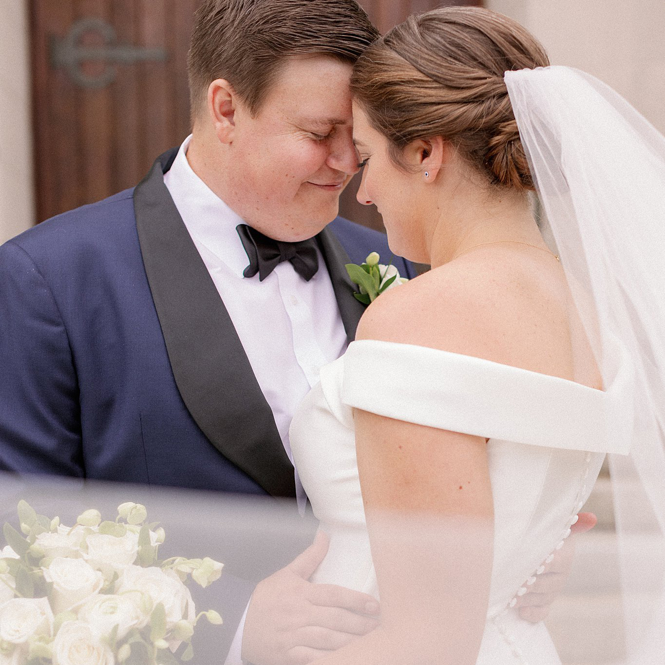 Bride and Groom embrace as her veil blows in the wind. Deborah Zoe Photography.