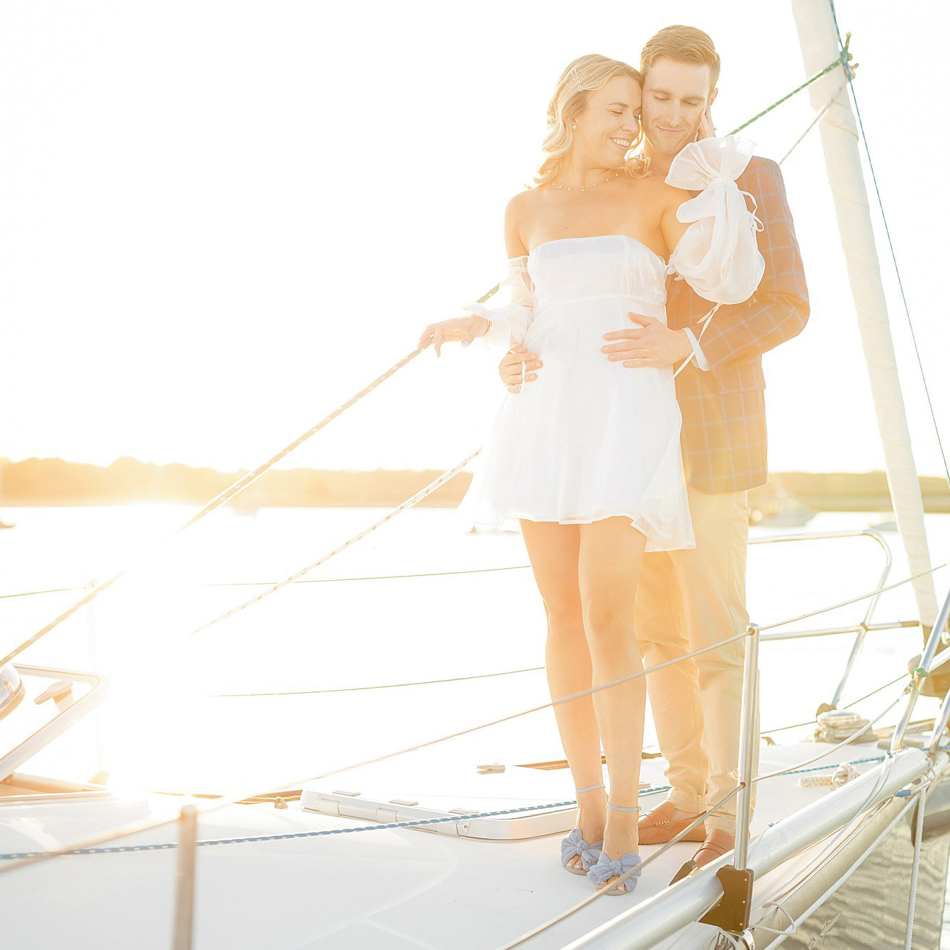 Couple embrace on sailboat during golden hour. Deborah Zoe Photography.