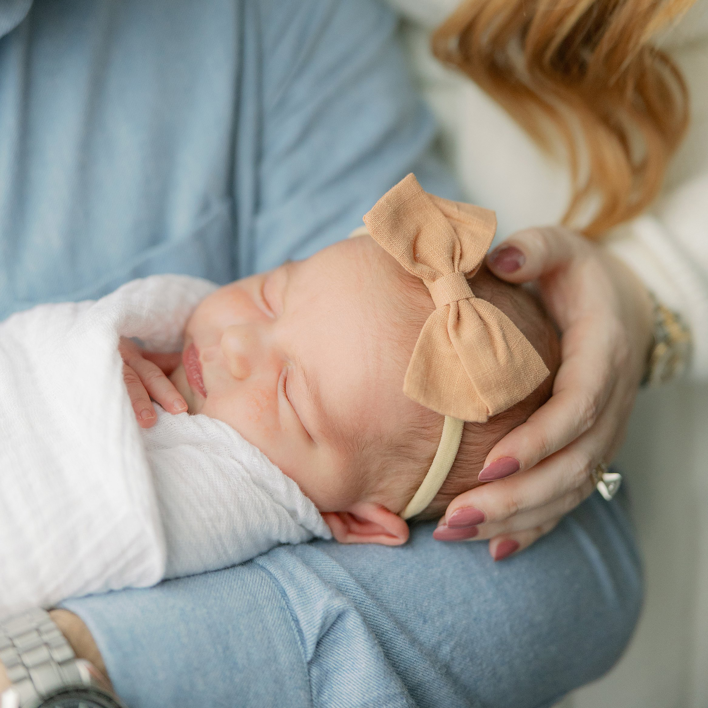 Newborn wearing peach bow held in Dad's arm. Boston Newborn Session Deborah Zoe Photography