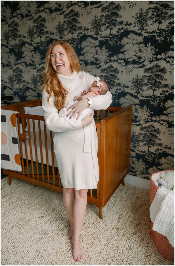 Mom with red hair laughs as she holds newborn in her arms. Boston Newborn Session Deborah Zoe Photography.