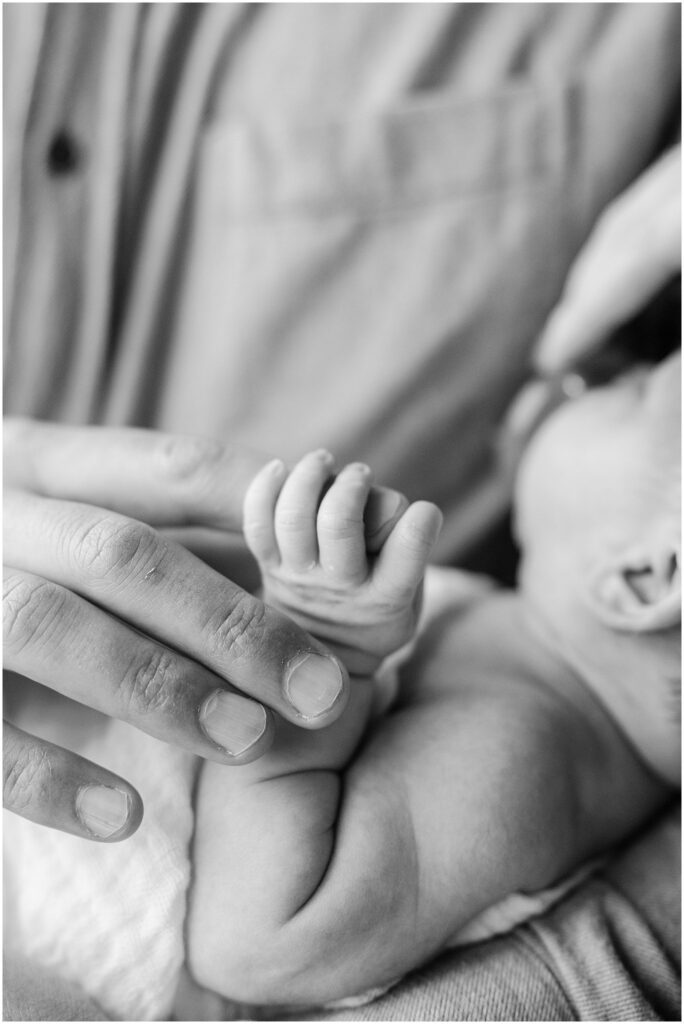 Black and white close up of newborn fingers holding her father's hands. Boston Newborn Session Deborah Zoe Photography.