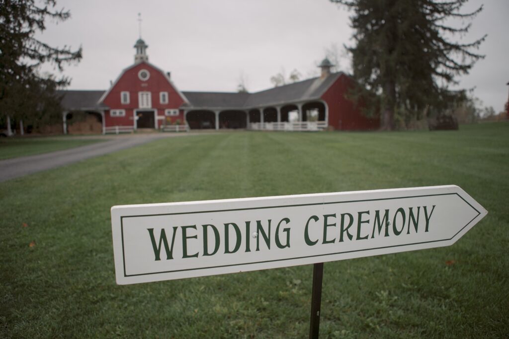 Wedding sign pointing to ceremony location in front of barn. Vermont Wedding Photographer Deborah Zoe Photography