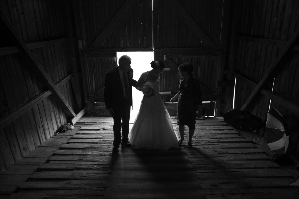 Bride and her parents are black lit as they walk into the ceremony space. Vermont Wedding Photographer Deborah Zoe Photography