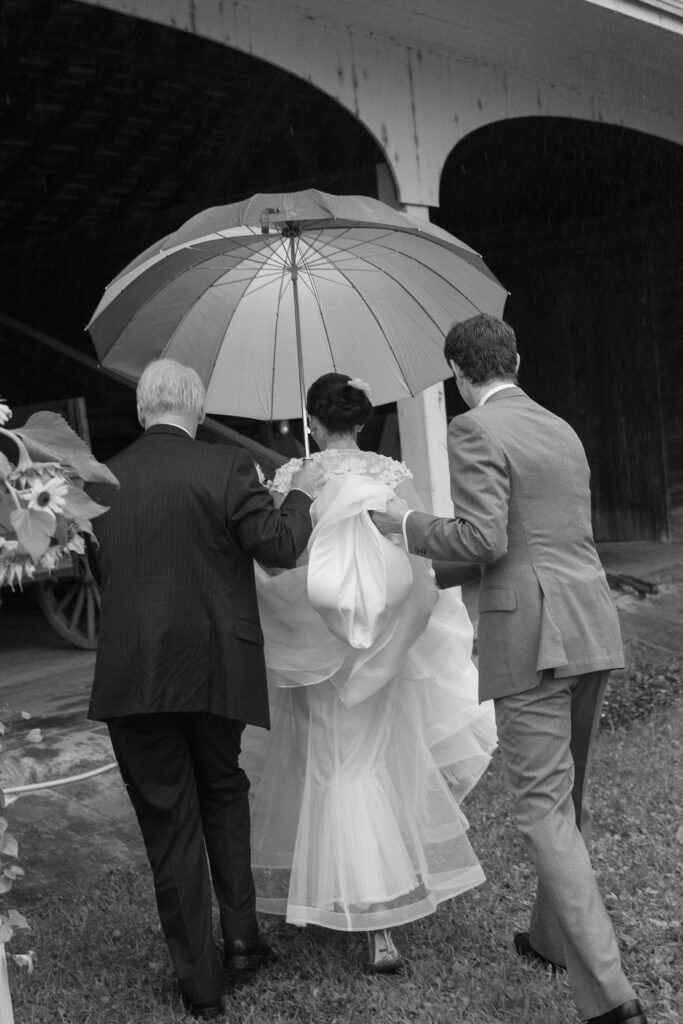 Bride is help under umbrella during wedding day. Vermont Wedding Photographer Deborah Zoe Photography