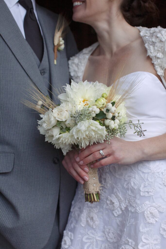 Close up detail of bride holding a wildflower bouquet with straw accents. Vermont Wedding Photographer Deborah Zoe Photography