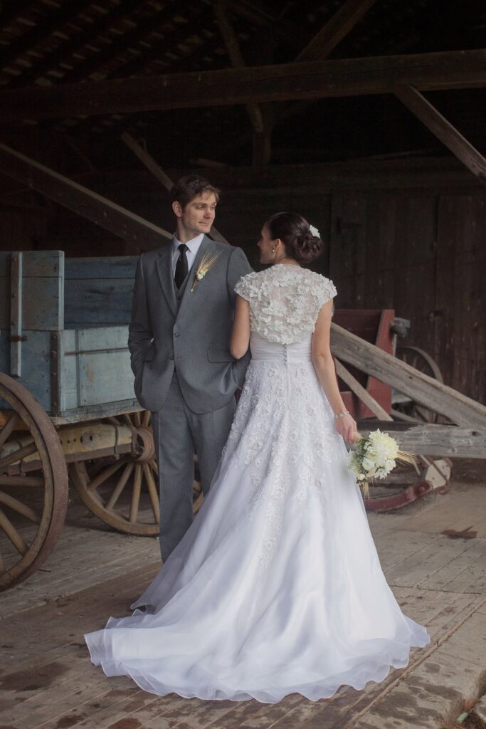 Bride and Groom portrait in barn showing elaborate back detail of wedding dress. Vermont Wedding Photographer Deborah Zoe Photography