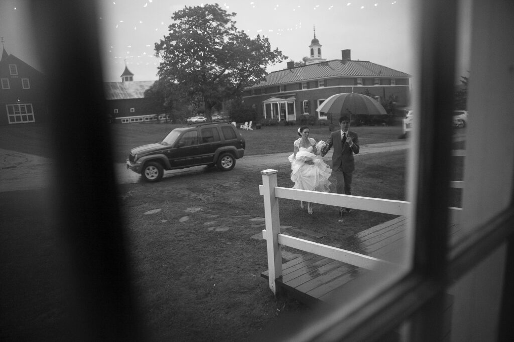 Bride and Groom walk into wedding reception as seen through a window. Vermont Wedding Photographer Deborah Zoe Photography