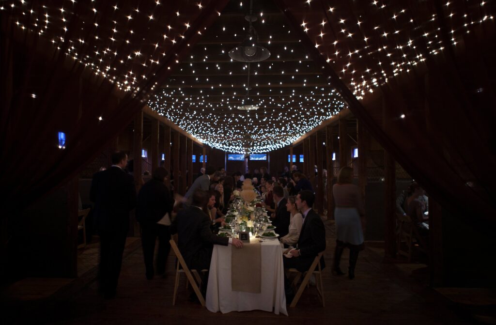 Guests eat dinner under twinkle lights during reception. Vermont Wedding Photographer Deborah Zoe Photography