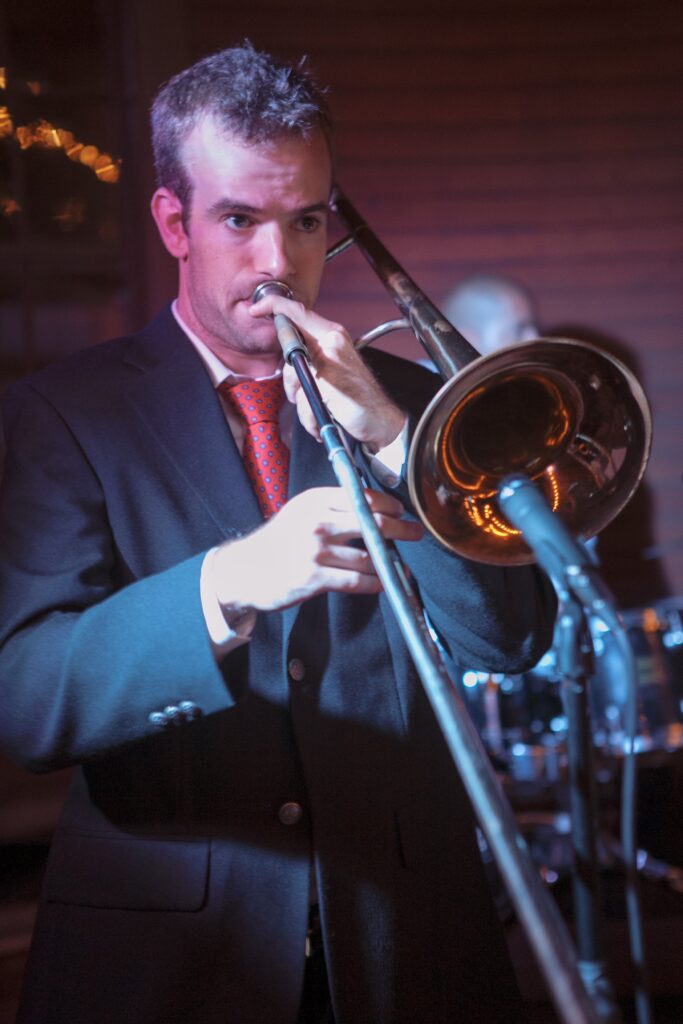 Man plays trumpbone during wedding reception. Vermont Wedding Photographer Deborah Zoe Photography