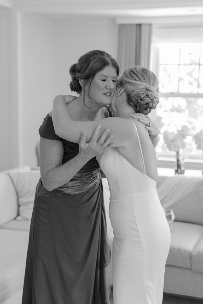 Bride hugs her mother while putting on her wedding dress. Modern Summer Wedding at the Newbury Boston Hotel photographed by Deborah Zoe Photography. 