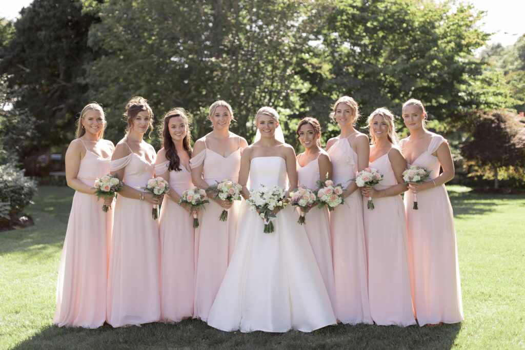 Bride stands with her bridesmaids in pink dresses. Coastal New England Wedding.