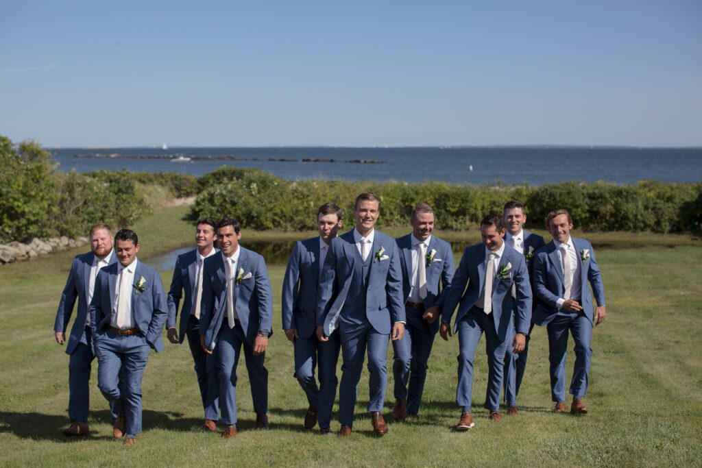 Groom and Groomsmen walking up hill with ocean behind them.