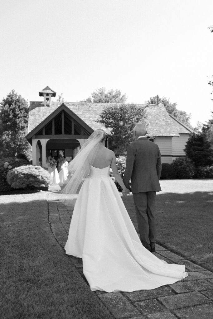 Bride holds her father's hand as they walk towards church on her wedding day. Coastal New England Wedding.