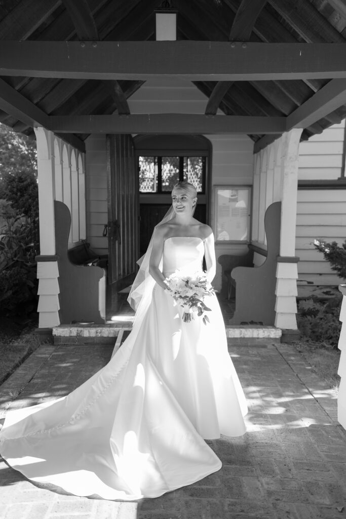 Black and white portrait of bride outside of church under entryway. Coastal New England Wedding.