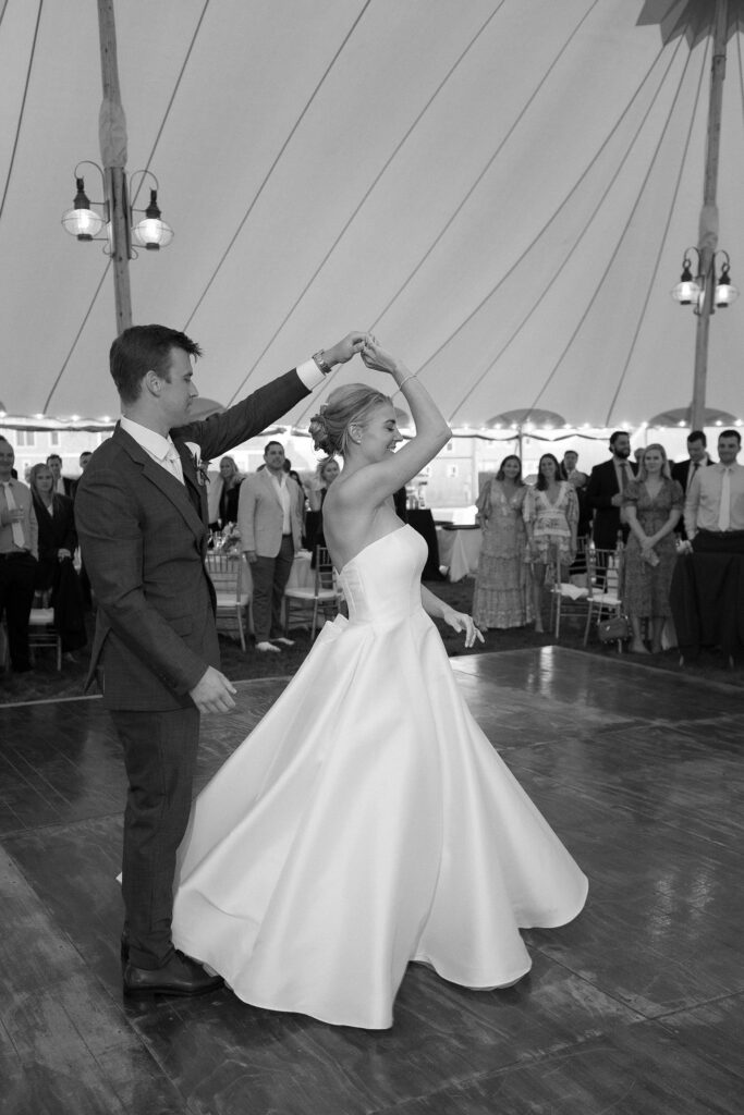 Groom twirls Bride during their first dance under a tent. Coastal New England Wedding.