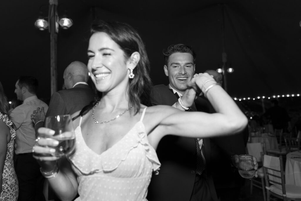 Guests celebrate and dance on the dancefloor during tented wedding reception. Coastal New England Wedding.