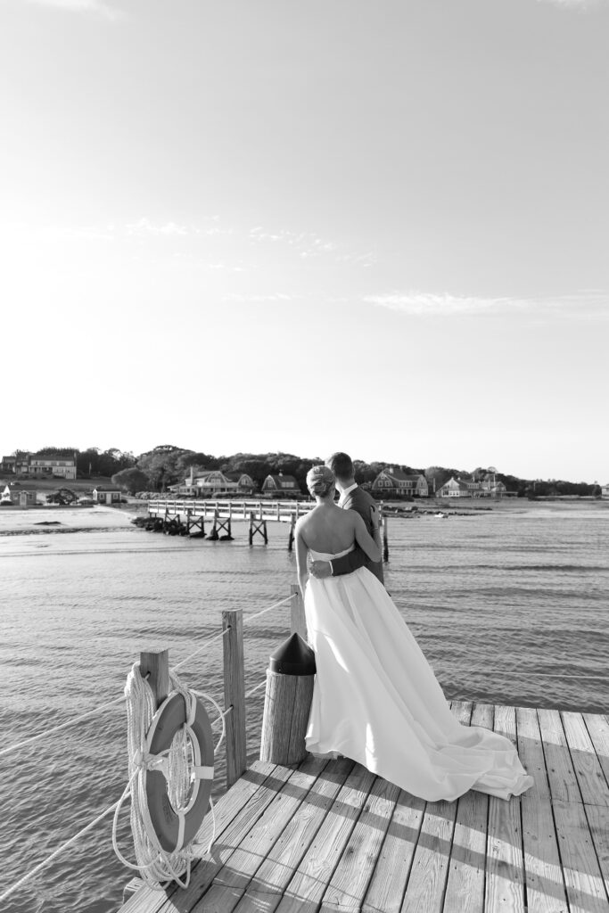 Bride and Groom pose together on a jetty with ocean behind them. Coastal New England Wedding.