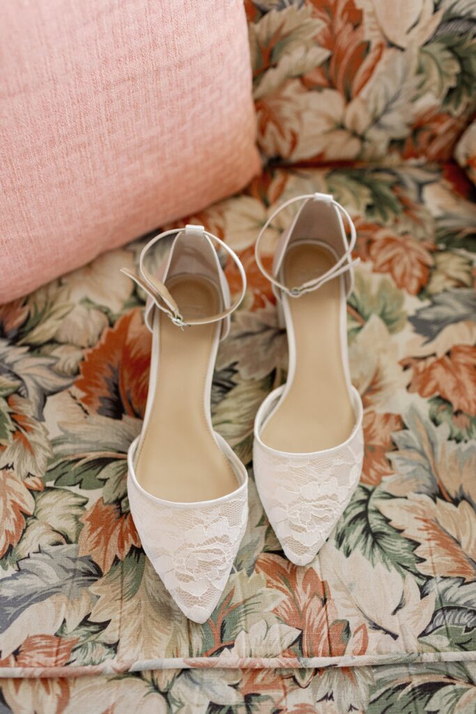 Close up detail of lace wedding shoes on a patterned couch cushion. Coastal New England Wedding.