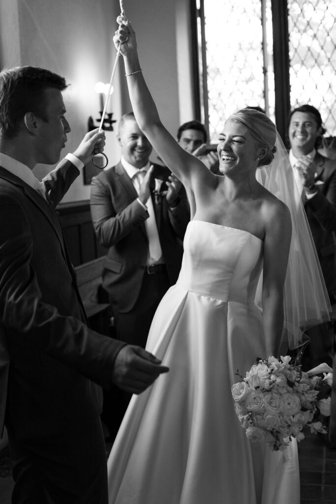 Bride and Groom ring church bell as they celebrate during their ceremony. Coastal New England Wedding.