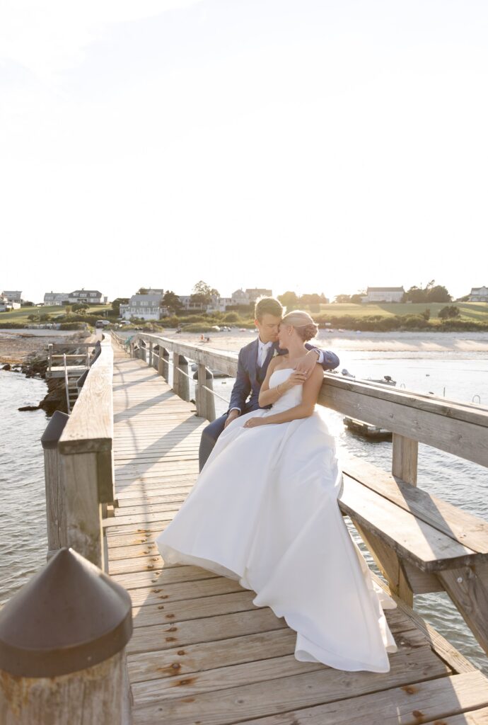 Bride and Groom pose together on a jetty with ocean behind them. Coastal New England Wedding.