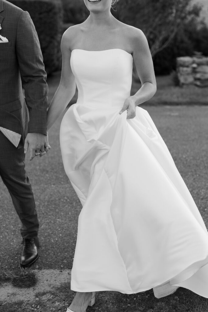 Close up detail of bride and groom walking hand in hand. Coastal New England Wedding.